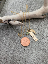 Load image into Gallery viewer, Gold tone necklace with birthstone crystal, bar with name and angel wing charm shown next to penny